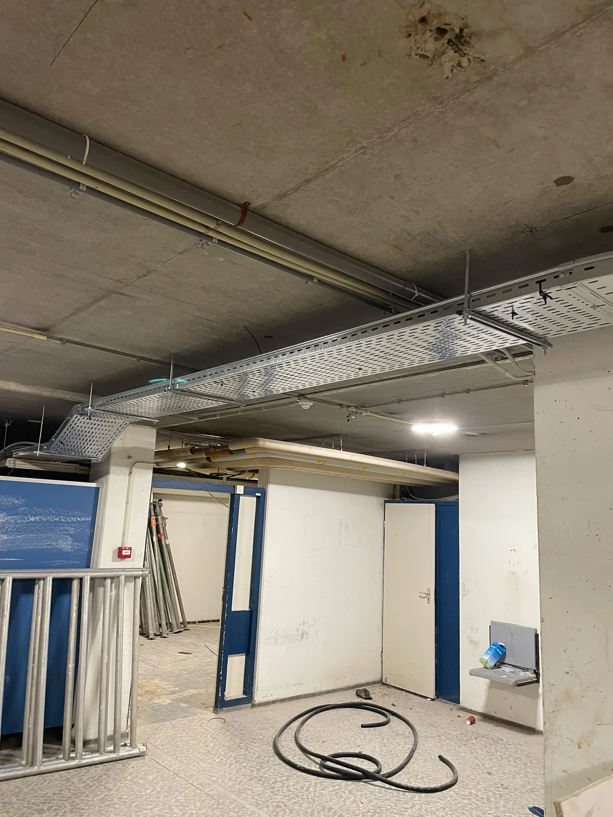 Kabelgoten en leidingwerk boven een bedrijfsruimte tijdens renovatie