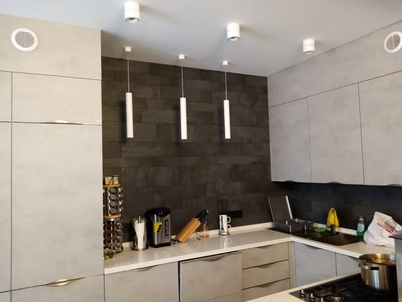 Keuken met inbouwspots en drie hanglampen boven het werkblad